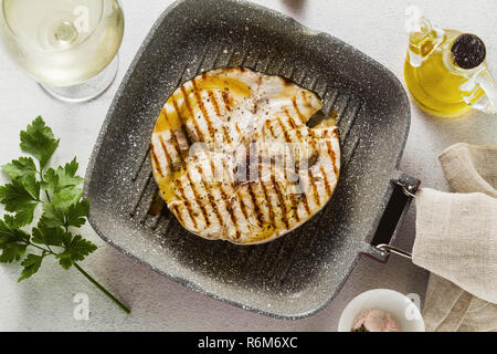 Schwertfisch Steak gebraten auf Grill Pfanne mit Olivenöl und Gewürzen. Weißwein Glas Stockfoto