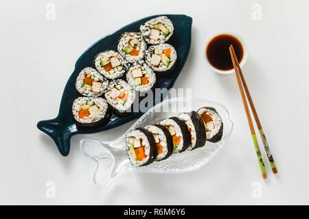 Vegan Ready-made Sushi auf dem Tisch in Fisch. Brötchen mit gebratenem Tofu, Gurken, gekochte Karotten und frischen Avocado. Gesunde vegane Ernährung Stockfoto