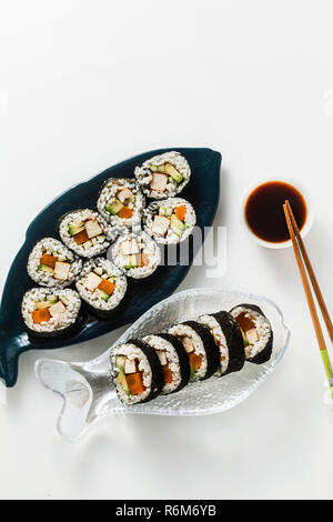 Vegan Ready-made Sushi auf dem Tisch in Fisch. Brötchen mit gebratenem Tofu, Gurken, gekochte Karotten und frischen Avocado. Gesunde vegane Ernährung Stockfoto