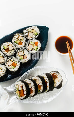 Vegan Ready-made Sushi auf dem Tisch in Fisch. Brötchen mit gebratenem Tofu, Gurken, gekochte Karotten und frischen Avocado. Gesunde vegane Ernährung Stockfoto