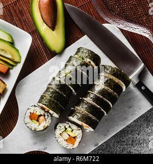 Vegan Ready-made Sushi auf dem Tisch in Fisch. Brötchen mit gebratenem Tofu, Gurken, gekochte Karotten und frischen Avocado. Gesunde vegane Ernährung Stockfoto