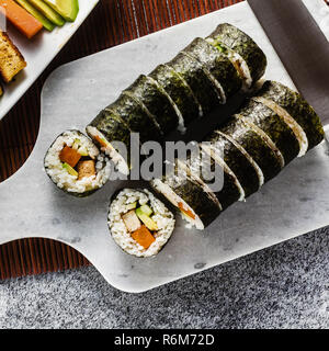 Vegan Ready-made Sushi auf dem Tisch in Fisch. Brötchen mit gebratenem Tofu, Gurken, gekochte Karotten und frischen Avocado. Gesunde vegane Ernährung Stockfoto