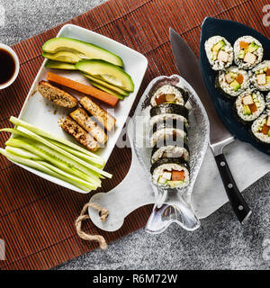 Vegan Ready-made Sushi auf dem Tisch in Fisch. Brötchen mit gebratenem Tofu, Gurken, gekochte Karotten und frischen Avocado. Gesunde vegane Ernährung Stockfoto