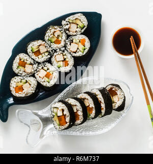 Vegan Ready-made Sushi auf dem Tisch in Fisch. Brötchen mit gebratenem Tofu, Gurken, gekochte Karotten und frischen Avocado. Gesunde vegane Ernährung Stockfoto