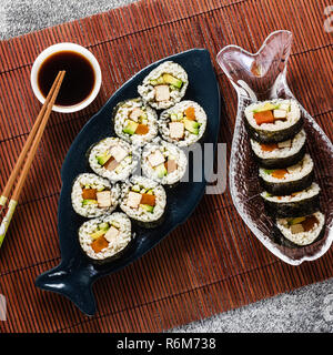 Vegan Ready-made Sushi auf dem Tisch in Fisch. Brötchen mit gebratenem Tofu, Gurken, gekochte Karotten und frischen Avocado. Gesunde vegane Ernährung Stockfoto
