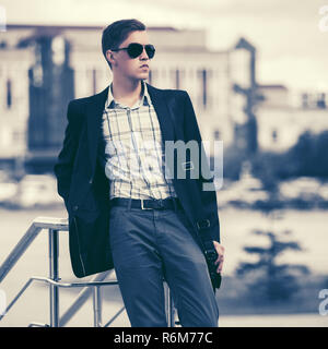 Junge gut aussehender Geschäftsmann in Sonnenbrille im city street Stilvolle männliches Modell in Schwarz Blazer Stockfoto