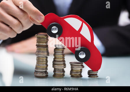 Geschäftsmann mit roten Auto über Gestapelte Münzen Stockfoto