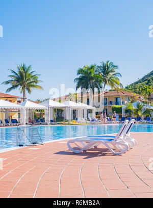 Zwei blaue lounge Zeichen neben einem unberührten schönen Swimmingpool in einem Resort in Kuba, Stockfoto