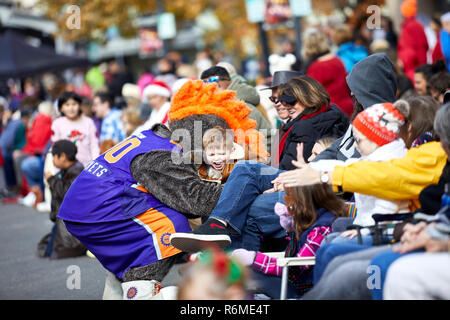 Prescott, Arizona, USA - Dezember 1, 2018: Mann mit einem Stier Kostüm mit einem Phoenix Suns Basketball einheitliche umarmt einen Jungen in der Menge während ma Stockfoto