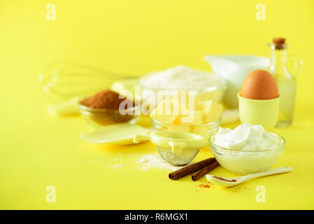 Urlaub Bäckerei Hintergrund. Essen frame-Butter, Zucker, Mehl, Milch, Eier, Öl, Löffel, Nudelholz, Pinsel, Schneebesen, Zimt auf gelben Hintergrund. Chri Stockfoto