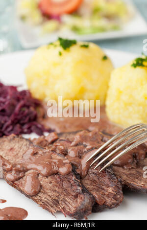 Sauerbraten mit Rotkohl auf einer Platte Stockfoto