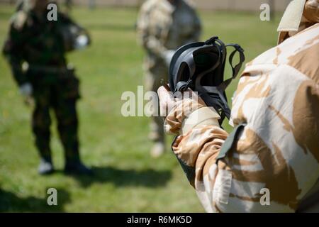 Eine britische Senior Noncommissioned Officer, mit der Gemeinsamen Europäischen Training Team, beschreibt die allgemeinen Service Atemschutzmaske außerhalb der US Army Training Support Center Benelux chemischen, biologischen, radiologischen und nuklearen Einrichtung auf der Air Base Chièvres, Belgien, 09. Mai 2017. Stockfoto