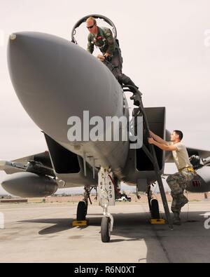 Oregon Air National Guard Kapitän Joshua Pfeifer, zu der 123 Fighter Squadron zugeordnet, Klettert eine Leiter an Bord eines F-15 Eagle, der 142 Fighter Wing zugeordnet, als Mannschaft Leiter Tech. Sgt. Ryan Johannes, bereitet Pfeifer mit seinem Flug auf der Nellis Air Force Base, Nev, 31. Mai 2017 zu unterstützen. Stockfoto