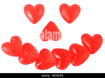 Leuchtend rote Gelee Herz geformten Süßigkeiten in Form eines lächelnden Happy Face auf weißem Hintergrund Stockfoto