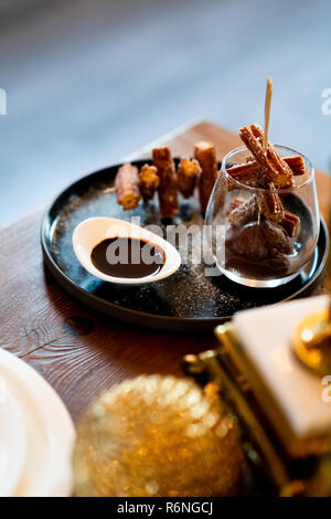 Elegante Churros mit Zucker und Schokolade Soße auf Fancy Anzeige in Glas und Platte Gastronomie Schließen Stockfoto