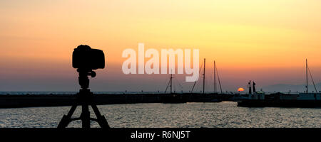 Kamera auf Stativ mit Blick aufs Meer und den Sonnenuntergang im Hintergrund Stockfoto