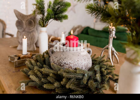 Weihnachten, brennende Kerzen mit Beeren und grüne Zweige. Hell leuchtendes candle.Composition mit Weihnachten Kerzen am Holztisch. Vorbereitung für die Partei. Hand Made Home Decor. Einrichtung Stockfoto