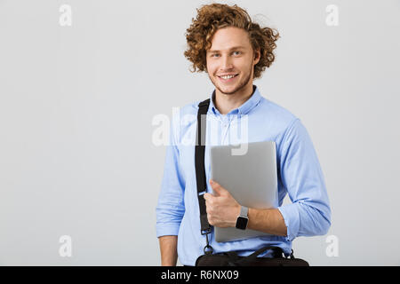 Lächelnde junge Unternehmer, die auf weißem Hintergrund, Tragetasche und Laptop Stockfoto