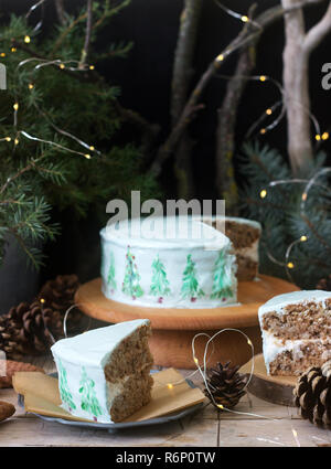 Festliche Kuchen mit gemalten Weihnachtsbaum auf einem dunklen Hintergrund der Zweige und Zapfen dekoriert. Im rustikalen Stil. Stockfoto