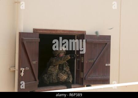 Ein Soldat von 3Rd Battalion, 8th Cavalry Regiment, 3. gepanzerte Brigade Combat Team, 1.Kavallerie Division wirft eine Simulation Granate in ein offenes Fenster eines benachbarten Haus während einer großen militärischen Übung in Südwestasien. Stockfoto