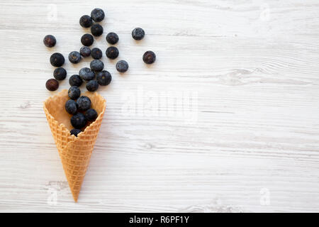 Süße Waffel Eiswaffel mit Blaubeeren auf weißem Holz- Oberfläche, Ansicht von oben. Flach, Overhead, von oben. Kopieren Sie Platz. Stockfoto