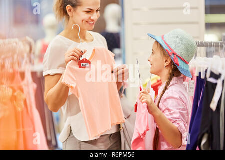 Mutter und Tochter sind auf der Suche nach Kleidung in einer Boutique während Verkauf Aktion Stockfoto