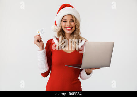 Portrait einer aufgeregt, blonde Frau in Rot neues Jahr Kostüm auf weißem Hintergrund gekleidet, mit Laptop Computer, anzeigen Kredit Auto Stockfoto