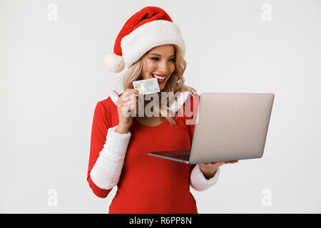 Porträt einer zufrieden blonde Frau in Rot neues Jahr Kostüm auf weißem Hintergrund gekleidet, mit Laptop Computer, Credit ca Stockfoto