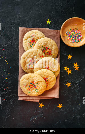 Im amerikanischen Stil, runde Plätzchen mit Konfetti (buttergebäck) auf einer Serviette auf einem schwarzen Stein Kulisse. Stockfoto