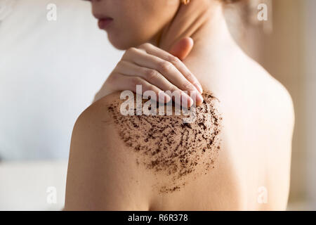 Beauty, Wellness und gesunde Haut Konzept - Frau reinigt die Haut des Körpers mit Kaffee Peeling im Badezimmer. Stockfoto