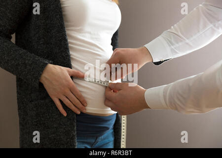 Schwangere Frau geprüft und durch einen Arzt mit einem Maßband gemessen Stockfoto