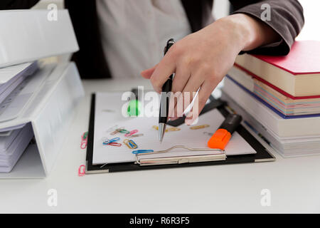 Frau am Tisch voller Papiere, Bücher, Dateien. Unordentlichen Arbeitsplatz. Überlast und Überarbeitung Stockfoto