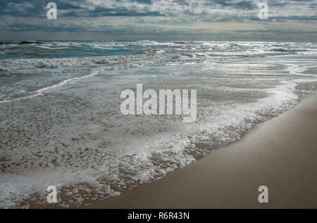 Ändern der Tide: ankommenden Wellen den Strand als ein dunkler Himmel beginnt bei Cape Hatteras National Seashore zu erleichtern. Stockfoto