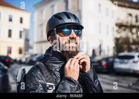 Männliche hipster Kurier setzen auf einen Helm in der Stadt, die Auslieferung von Paketen. Kopieren Sie Platz. Stockfoto