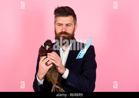 Bärtige Geschäftsmann. Hipster. Crazy man auf Rosa. Mann mit Geflügelfleisch. Verrückte Werbung. Ungewöhnliche Idee. Kreative Idee. Vogelgrippe. Lustige Werbung. glücklicher Mann halten Fasan Stockfoto