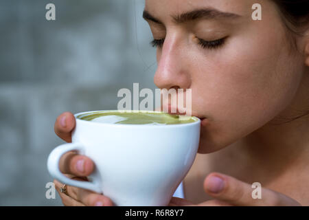 Matcha Latte Tee Zeremonie des Mädchens. Frau trinken Japanische Tee aus dem Becher. die Frau im Cafe und Trinken entspannen. Perfekte morgen mit grünem Kaffee. Die Ausgaben viel Zeit zu Hause. Mehr Kaffee. Frischen Kaffee Stockfoto