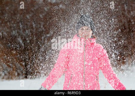 Glückliche junge Frau spielt mit Schnee im Park. Winter Konzept. Stockfoto