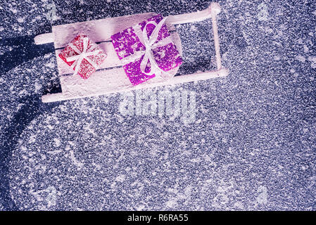 Santa sleigh mit geschenkboxen über verschneite Hintergrund. Stockfoto