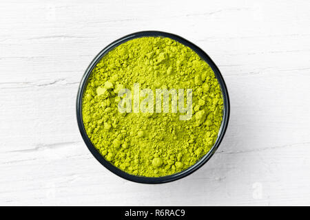 Matcha Grüntee Pulver in einer Schüssel auf weißem Holz- Hintergrund, Blick direkt von oben. Stockfoto