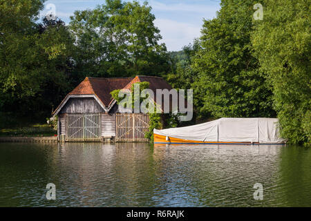 Ein altes Bootshaus und klassischen Mahagoni starten unter einer Plane auf der Themse bei Mill End, Buckinghamshire Stockfoto