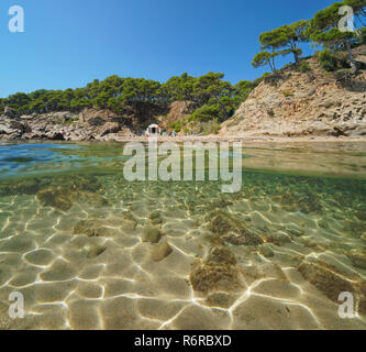 Mediterrane Cove im Sommer mit Fels und Sand unter Wasser, geteilte Ansicht Hälfte oberhalb und unterhalb der Wasseroberfläche, Cala Estreta, Palamos, Spanien, Costa Brava Stockfoto