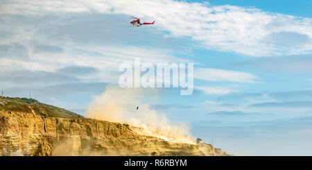Hubschrauber im Flug an bewölkten Himmel über einer Klippe Stockfoto