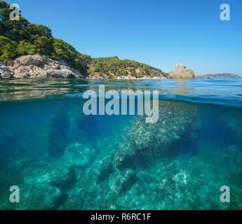 Felsige Küste mit grossen Felsen unter Wasser Meer, geteilte Ansicht Hälfte oberhalb und unterhalb der Wasseroberfläche, Mediterran, Palamós, Costa Brava, Spanien Stockfoto