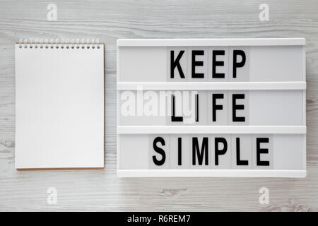 'Keep life simple' Wörter auf modernen Board, leere Notepad über weiß Holz- Oberfläche, Ansicht von oben. Flach, von oben. Platz für Text. Stockfoto