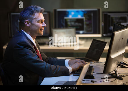 Geschäftsmanns, der auf mehreren Computern Stockfoto