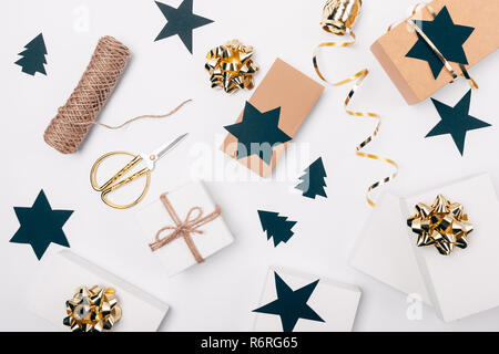 Stilvolle flach Anordnung der Verpackung Weihnachtsgeschenke mit den goldenen Bögen, Kartons, Papier - schwarze Sterne ausschneiden und Pinien, Ansicht von oben. Stockfoto