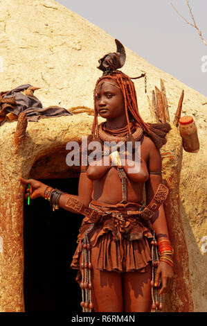 Frau Himba vor seiner Lehmhütte in der Nähe von Epupa Wasserfälle, Namibia Stockfoto