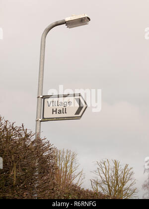 Weiß und schwarz Village Hall Schild Richtung Straße Stockfoto