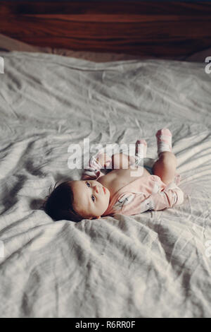 Portrait von cute adorable Lustig weiß Kaukasischen brunette little baby Neugeborenen das Tragen von Windeln und liegend auf Bett im Schlafzimmer. Authentischen Lebensstil candid re Stockfoto