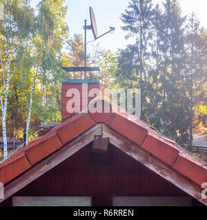 Prüfung der roten Ziegeldach ein freistehendes Haus, mit Kamin und Sat-Antenne. Stockfoto